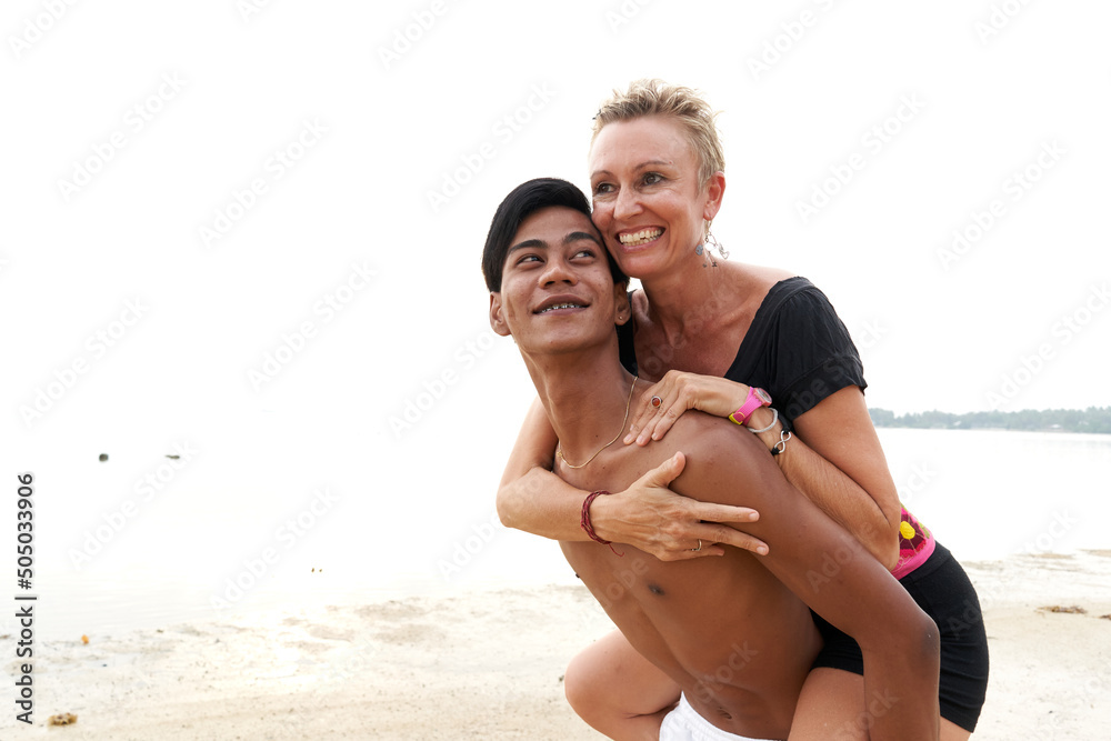 Fototapeta premium Couple in love piggyback riding on a tropical beach