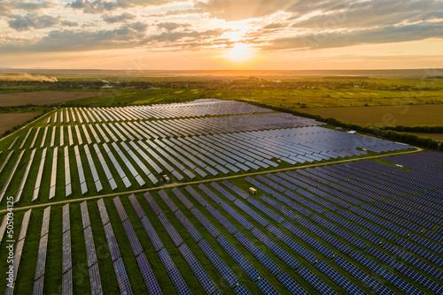 Aerial view of large sustainable electrical power plant with many rows of solar photovoltaic panels for clean ecological electric energy at sunrise. Renewable electricity with zero emission concept