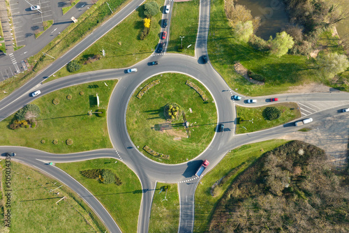 Aerial view of road roundabout intersection with moving heavy traffic. Urban circular transportation crossroads
