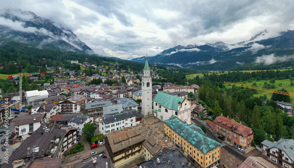 Panorama drone view of the Basilica Minore dei Santi Filippo e Giacomo standing in the town of Cortina d'Ampezzo in the Dolomites mountains