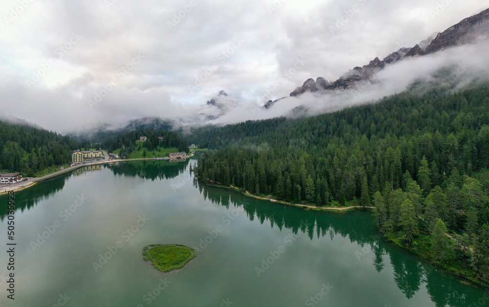 Panorama drone view of Lago di Misurina, reflection of the mountain in the lake, flying through the fog in the Dolomites in Italy