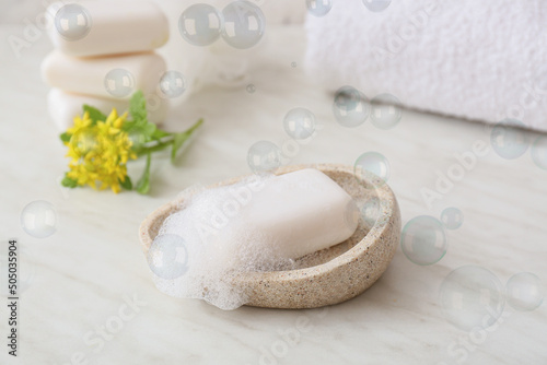 Soap bar with foam on light background