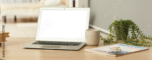 Modern laptop, houseplant a...