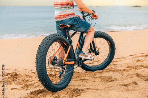 Fat bike on the beach with unrecognizable guy riding on it photo