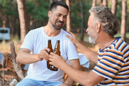 Canvas Print Handsome man with his father drinking beer in forest