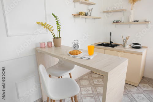 Dining table with breakfast and alarm clock in modern kitchen