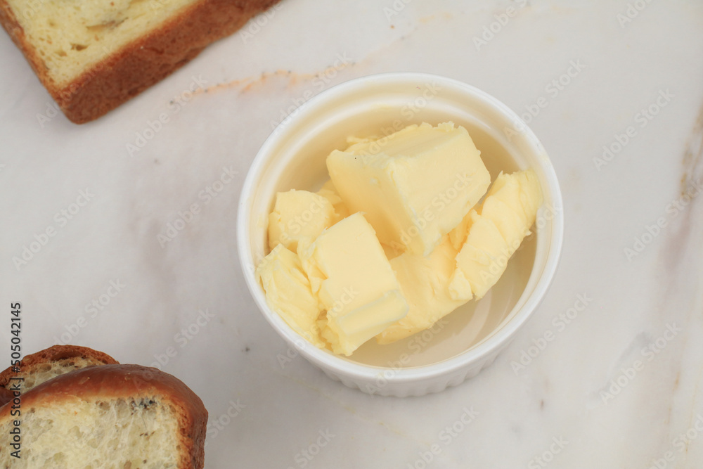 Butter pieces in bowl on white background. Farm dairy products. Selective focus. Butter pieces in bowl on white background. Farm dairy products. Selective focus.