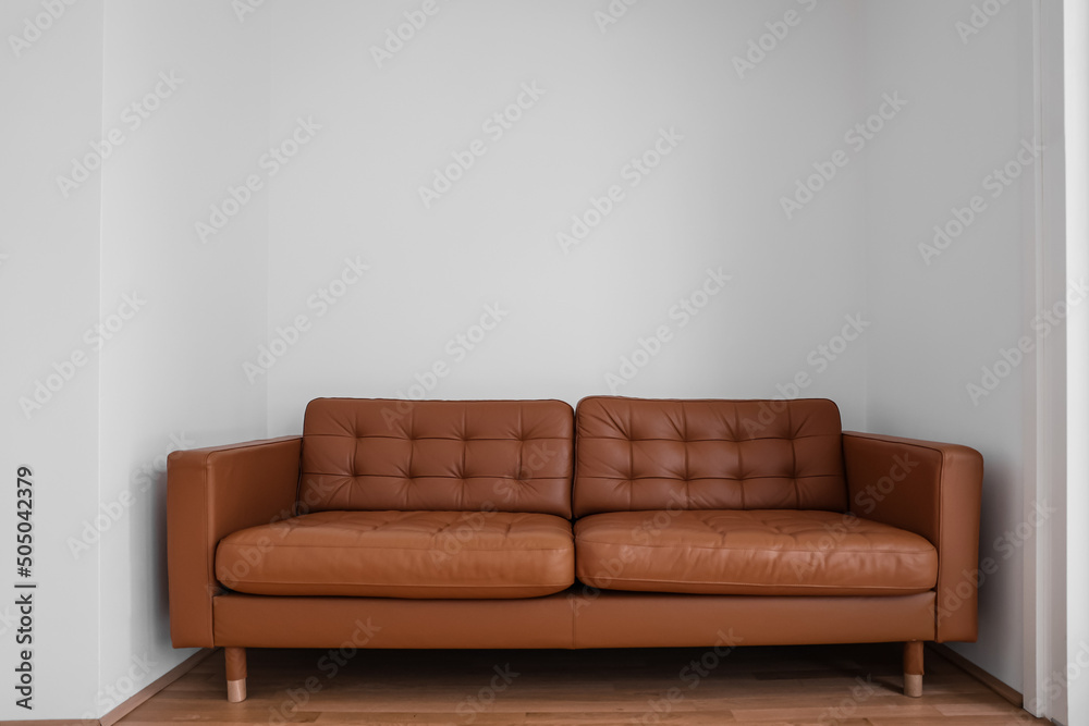Brown leather couch near light wall in room Stock Photo | Adobe Stock