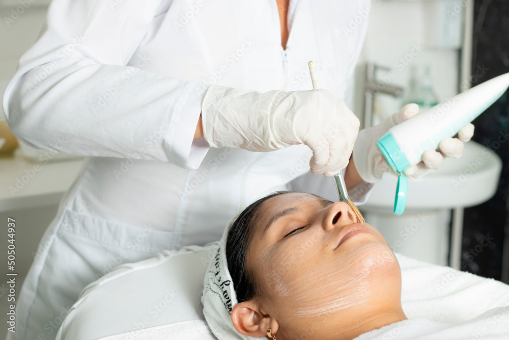 Naklejka premium Latina woman with skin treatment, Hispanic doing laser hair removal underarms, dermatology clinic in Costa Rica. Skin treatment, acne and hair removal. Copy space for advertising and blurred backgroun
