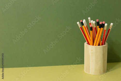 Pencils in holder on desk. khaki green background