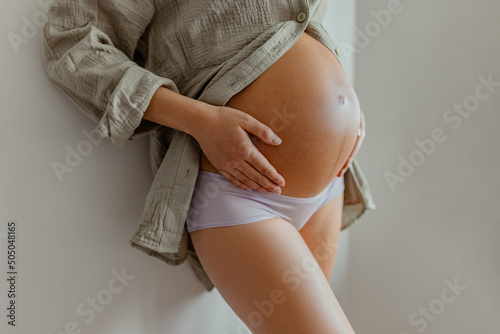 Canvastavla Pregnant woman wearing maternity underwear pajamas at home relaxing holding expecting tummy for skincare, health, lifestyle
