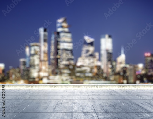 Empty concrete dirty rooftop on the background of a beautiful blurry New York city skyline at night, mock up