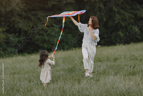 Slika na platnu Mother and daughter playfull with kite at the sunny meadow
