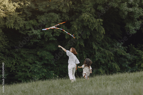 Fotografija Mother and daughter playfull with kite at the sunny meadow