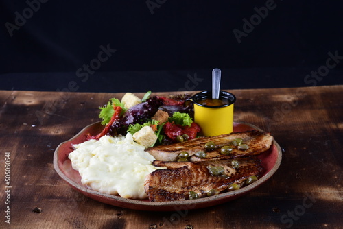 plate with meat filet fish with mashed potatoes, salad with herbs sauce