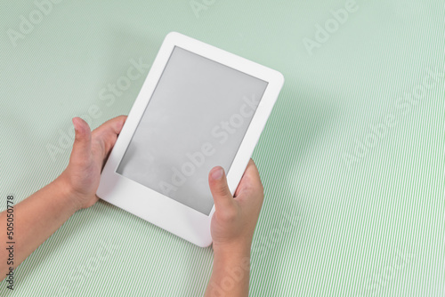 Ebook reader over green background - being held by the hand of a child photo