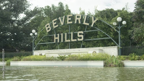 Static shot of Beverly Hills sign, trees, and pond