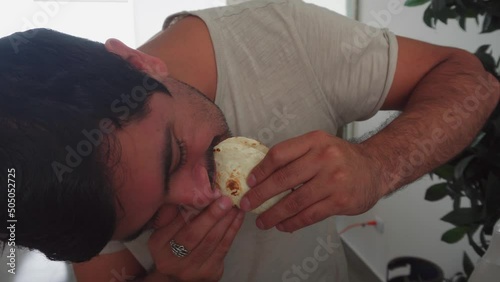 closeup of a man eating a homemade taco with his hands in the kitchen in 4k