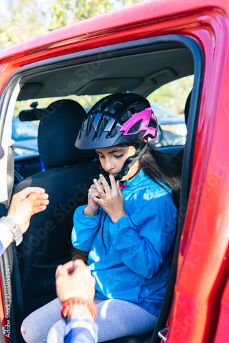 Girl putting on a protective helmet inside a vehicle © FABIAN PONCE GARCIA