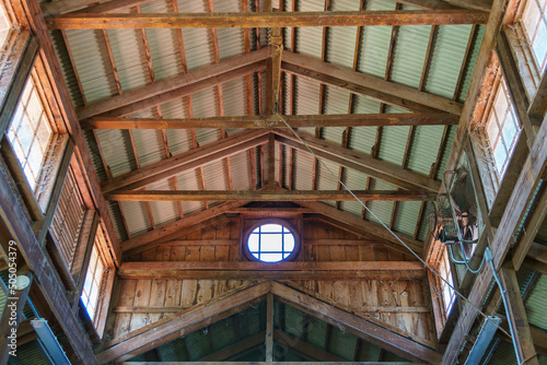Barn ceiling with crossbeams and corrugated metal roof, circular window. photo