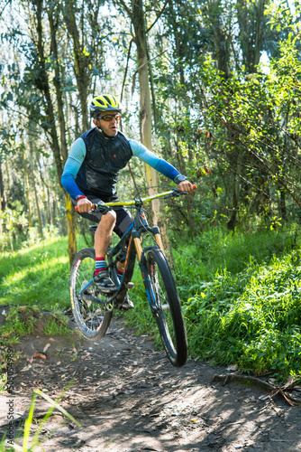 Man with helmet and goggles jumping on his mountain bike in a forest