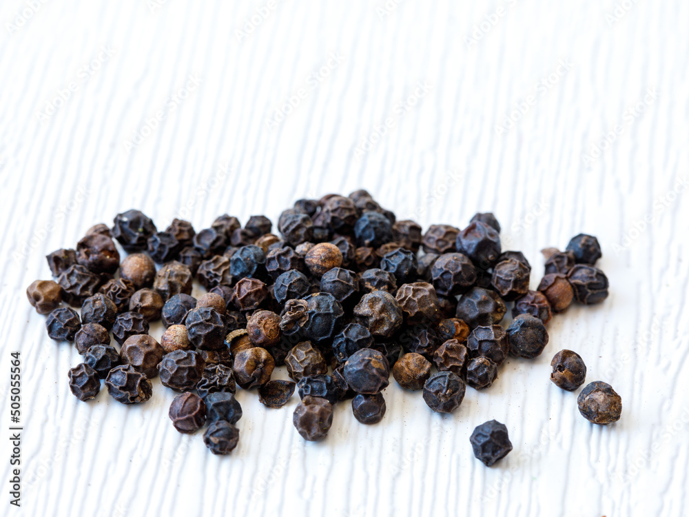 top view of handful of dried black pepper peppercorns (dry ripe piper nigrum fruits) on white wooden background. Close up full frame food background top view of handful of dried black pepper peppercorns (dry ripe piper nigrum fruits) on white wooden background. Close up full frame food background