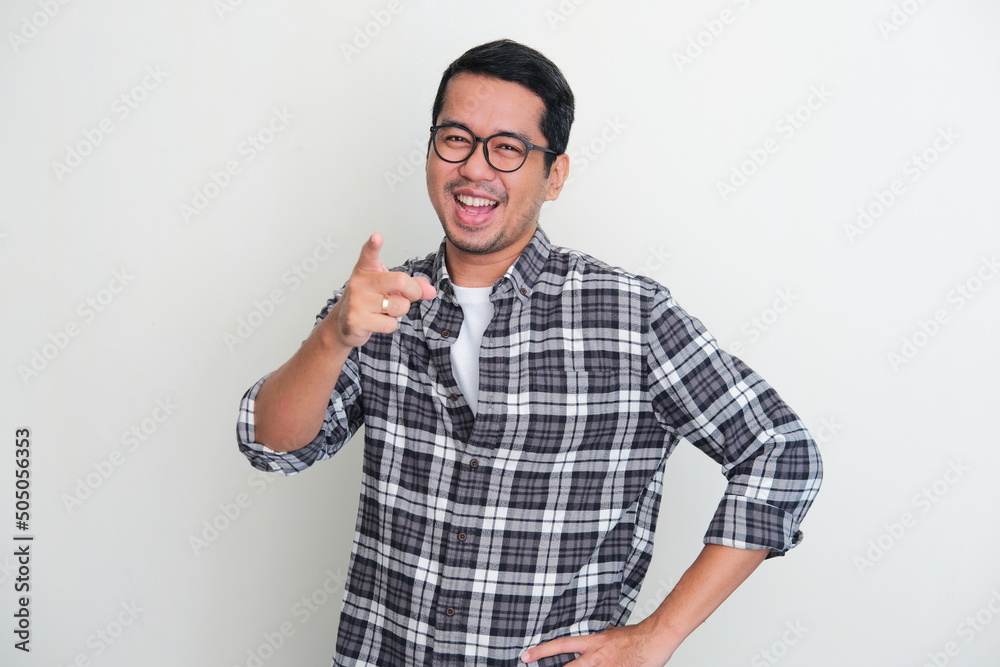 Adult Asian man showing excited expression while pointing finger forward Adult Asian man showing excited expression while pointing finger forward