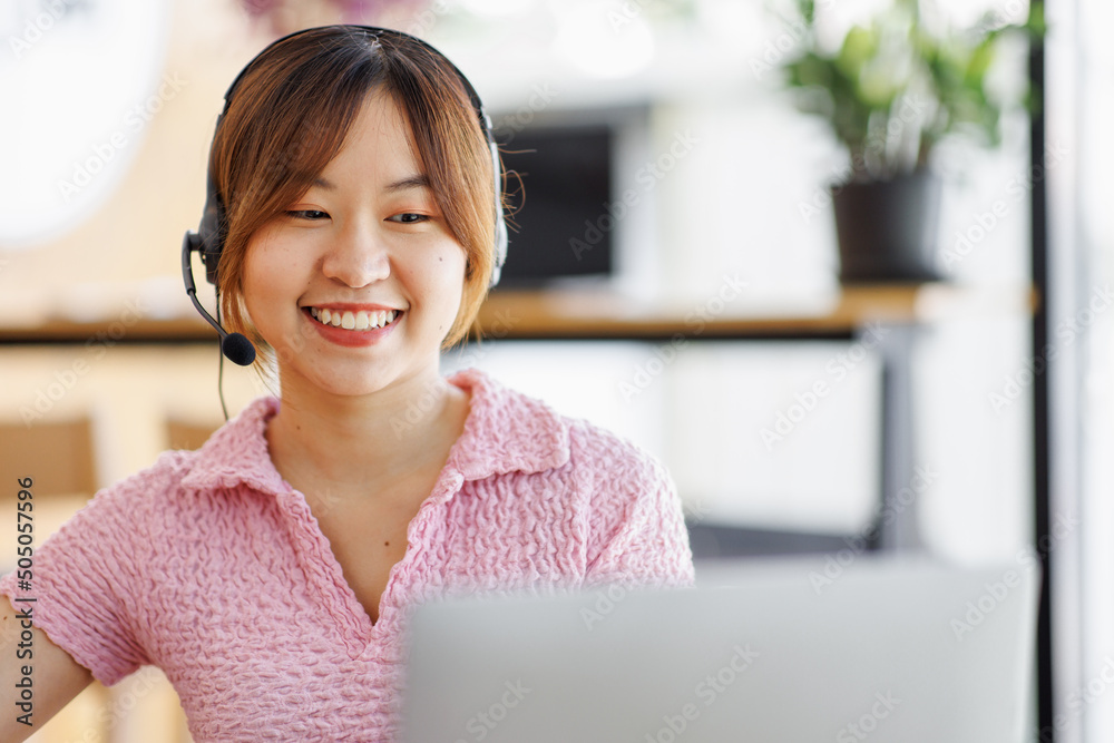 Young adult happy smiling Hispanic Asian student wearing headphones talking on online chat meeting using laptop in university campus or at the coffee shop. College female students learning remotely. Young adult happy smiling Hispanic Asian student wearing headphones talking on online chat meeting using laptop in university campus or at the coffee shop. College female students learning remotely.