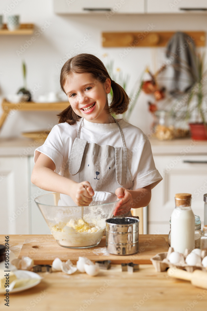 Happy child girl cooking pastry in kitchen Happy child girl cooking pastry in kitchen