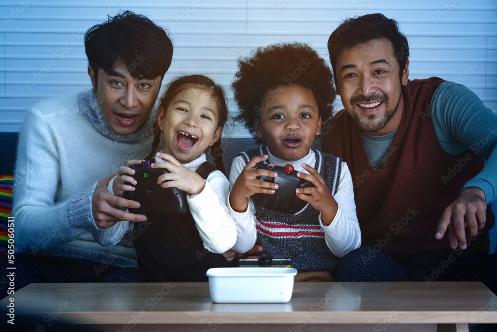 Φωτογραφία Male gay couple having fun with kids playing video game console, LGBTQ family co