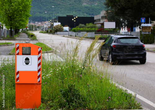 Big orange Safety Speed Camera and a black car on the road photo