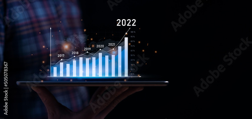 Business growth and progress concept. Businessman is showing virtual hologram chart from tablet. plans to increase business growth and an increase in the indicators of positive growth in 2022
