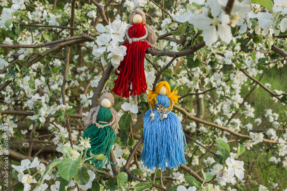 Group of three handmade faceless doll knitted from a red, green and blue threads. Macrame technique. Eco decoration.