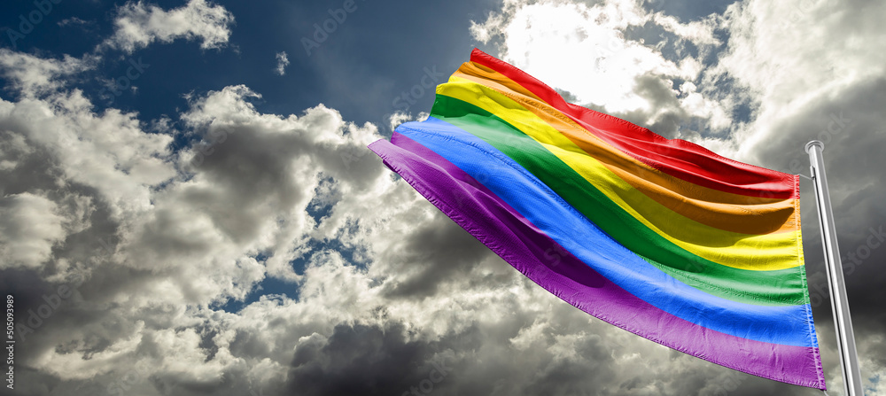 Pride rainbow lgbt gay flag being waved in the breeze against a sunset ...