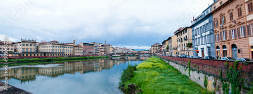 Overgrown Arno river waterfront with Ponte Santa Trinita StTrinity bridge in Florence, Italy