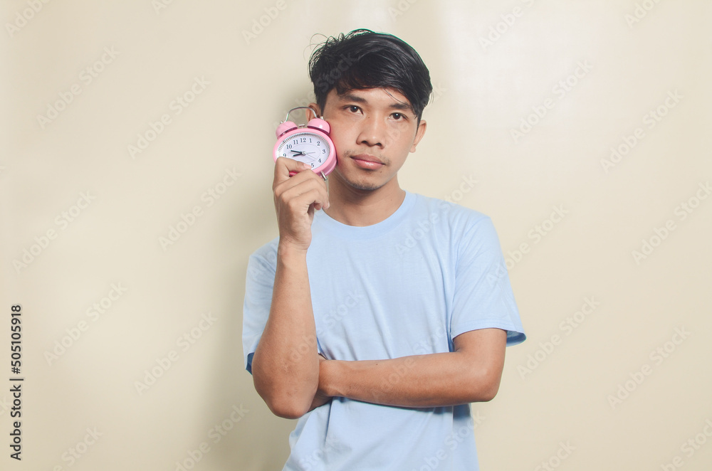 Portrait of asian young man carrying alarm clock isolated background Portrait of asian young man carrying alarm clock isolated background