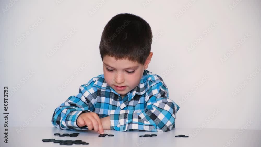 A 4-year-old boy is learning to count, teaching black numeracy chips for preschoolers A 4-year-old boy is learning to count, teaching black numeracy chips for preschoolers