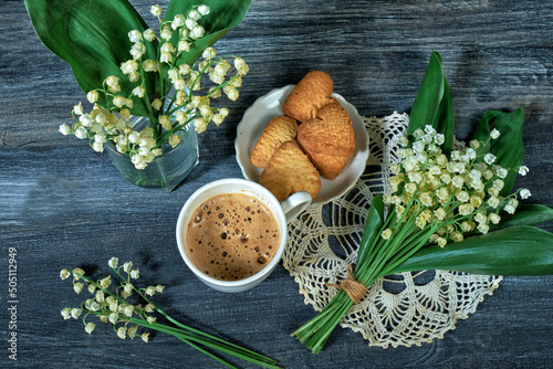 cup of coffee and lilies of the valley on wooden background