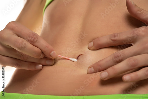 Woman cleaning her belly button with cotton swab , Cropped image, close up photo