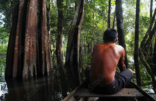 Caboclo man riding a canoe in an amazon rainforest mangrove near Belém, Pará, Brazil.