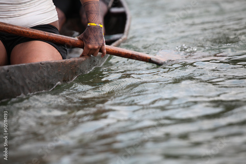Schilderij op canvas Detail of a woman rowing, traveling on a rudimentary wooden canoe on the Xingu River, Amazon,Brazil