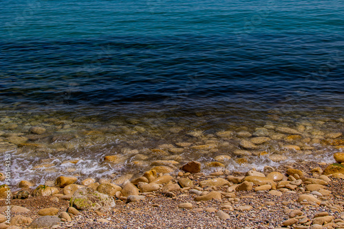 calm gentle background of blue sea and shore with beige stones © Joanna Redesiuk