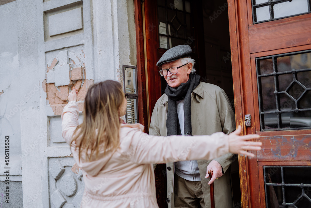 Adult daughter greeting her senior father when meeting him outdoors in street.