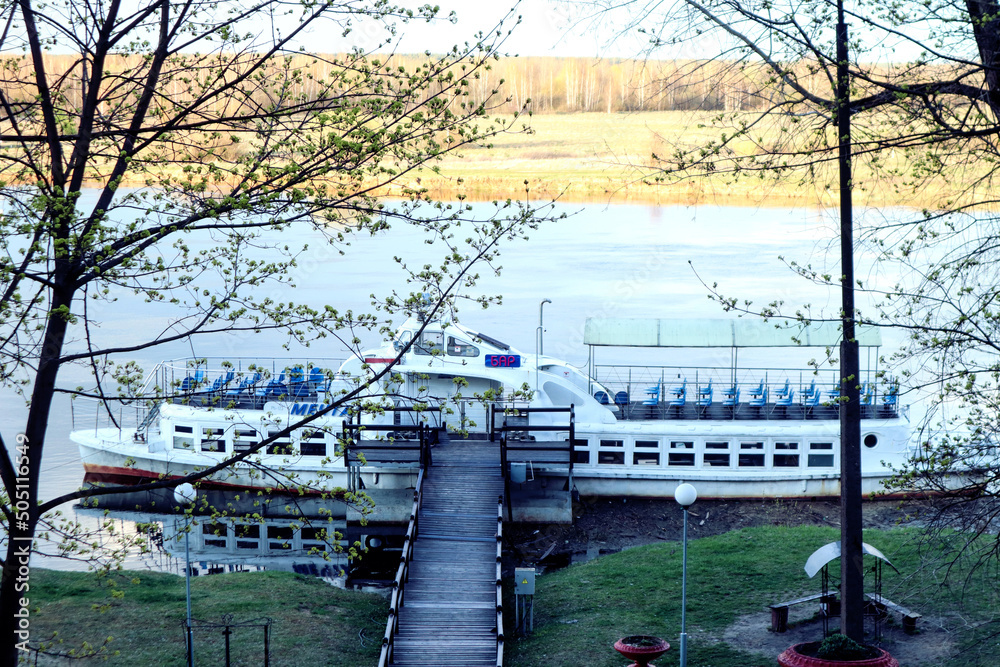 Fototapeta premium View from the stairs to a small motor ship on a spring day, blue sky background, spring landscape
