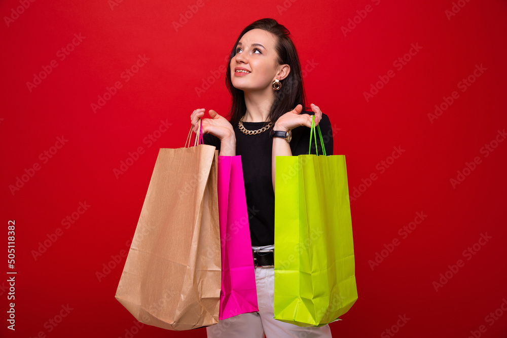 A young woman with colorful shopping bags on a red background