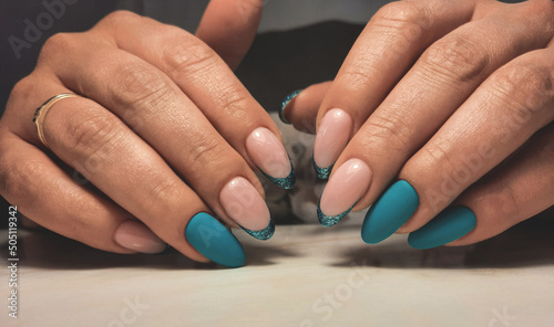 Round nails with a turquoise gel polish and French design. Women s manicure with camouflage gel polish and marine French design