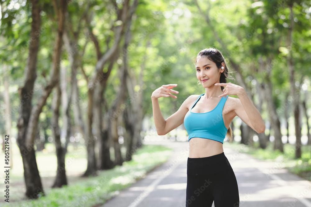 Young athletic woman stretching herself in park and using bluetooth headphones listen music. Portrait of beautiful sportswoman. Young athletic woman stretching herself in park and using bluetooth headphones listen music. Portrait of beautiful sportswoman.