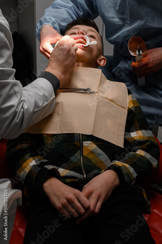 Alignment of crooked teeth with the help of braces, installation of braces for a child, an orthodontist glues metal plates braces for teeth alignment. photo