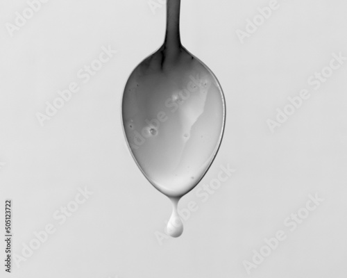 Fresh yogurt on a spoon isolated on white. Delicious yogurt drips from the spoon. Liquid drops. Image for dairy product packaging design.