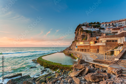 Picturesque village Azenhas do Mar. Holiday white houses on the edge of a cliff with a beach and swimming pool below. Landmark near Lisbon, Portugal, Europe. Landscape at sunset. photo